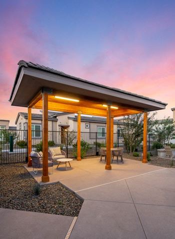 a covered patio with tables and chairs at sunset at Grandstone at Sunrise, Peoria, AZ